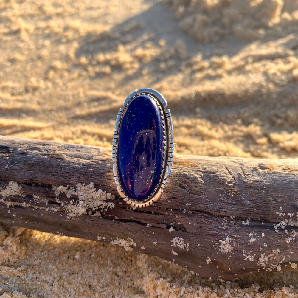 Bague Lapis Lazuli posée sur un bois flotté à la plage